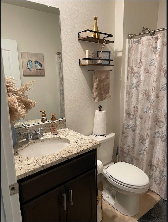 bathroom featuring vanity, tile patterned floors, and toilet