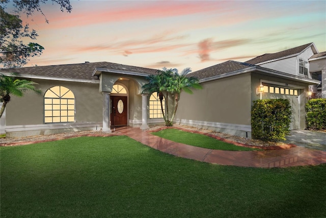 view of front of home with a garage and a lawn