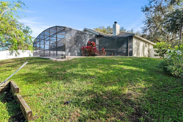 back of property featuring glass enclosure and a lawn