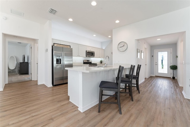 kitchen with sink, a breakfast bar area, white cabinetry, light hardwood / wood-style flooring, and appliances with stainless steel finishes