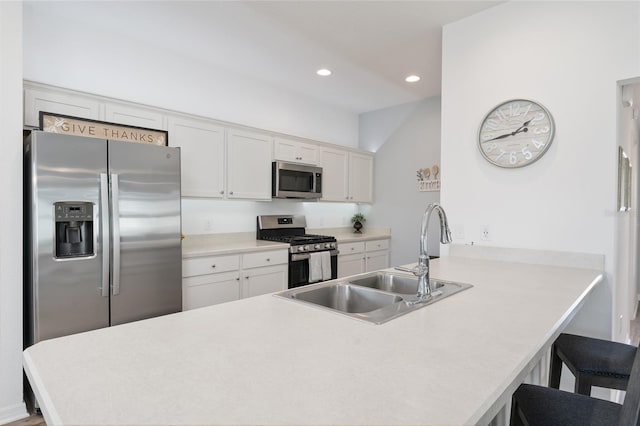 kitchen with sink, appliances with stainless steel finishes, a kitchen breakfast bar, white cabinets, and kitchen peninsula