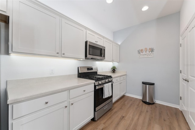 kitchen with stainless steel appliances, white cabinetry, and light wood-type flooring