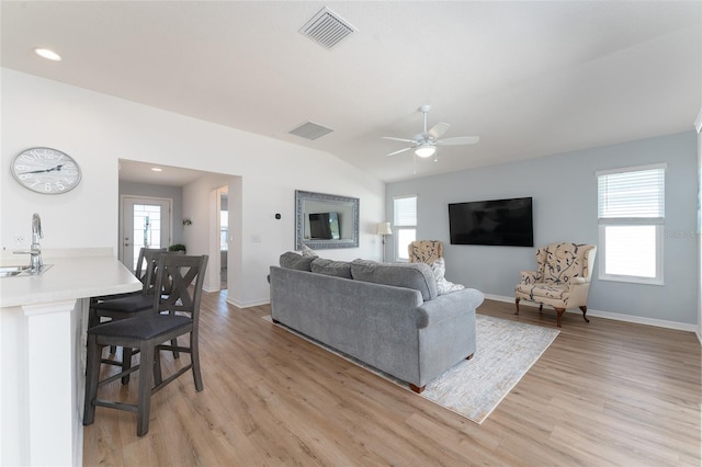 living room with sink, light hardwood / wood-style floors, and a wealth of natural light