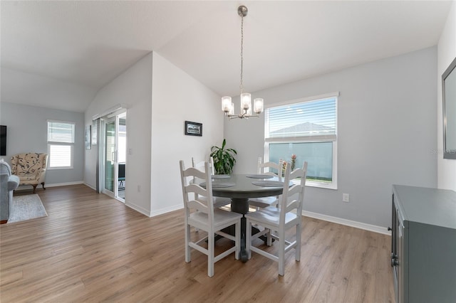 dining room with vaulted ceiling, plenty of natural light, a chandelier, and light hardwood / wood-style flooring