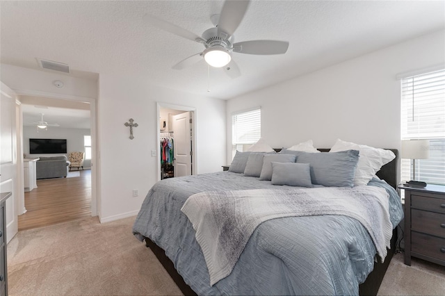 carpeted bedroom featuring ceiling fan, a spacious closet, a closet, and a textured ceiling