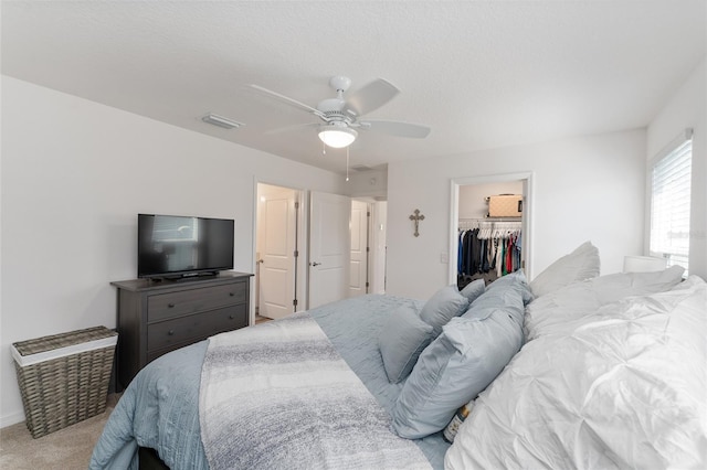 carpeted bedroom with a spacious closet, a closet, and ceiling fan