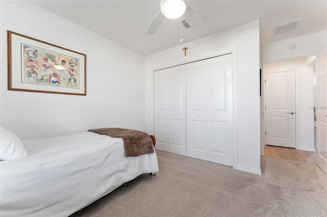 bedroom featuring light colored carpet, ceiling fan, and a closet