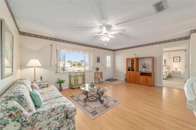 living room with hardwood / wood-style flooring, ceiling fan, and a textured ceiling