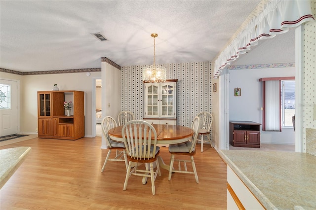 dining area featuring a chandelier, a textured ceiling, and light wood-type flooring