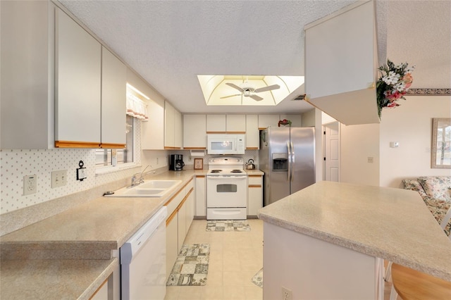 kitchen with a kitchen bar, sink, white appliances, kitchen peninsula, and ceiling fan