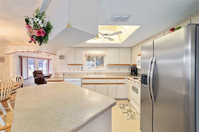 kitchen with white cabinetry, sink, a textured ceiling, and white appliances