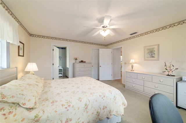 carpeted bedroom with multiple windows, a textured ceiling, ensuite bath, and ceiling fan