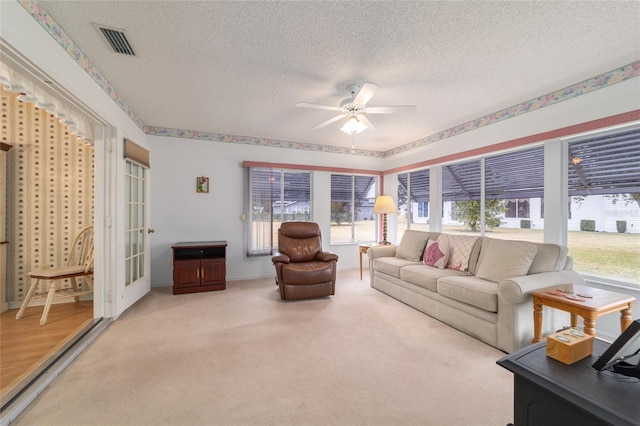 carpeted living room with ceiling fan and a textured ceiling