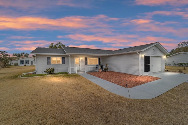 single story home with a porch, a garage, and a lawn