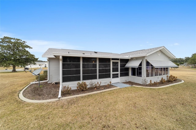 back of property featuring a sunroom and a lawn