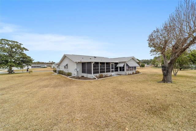 rear view of property featuring a lawn and a sunroom