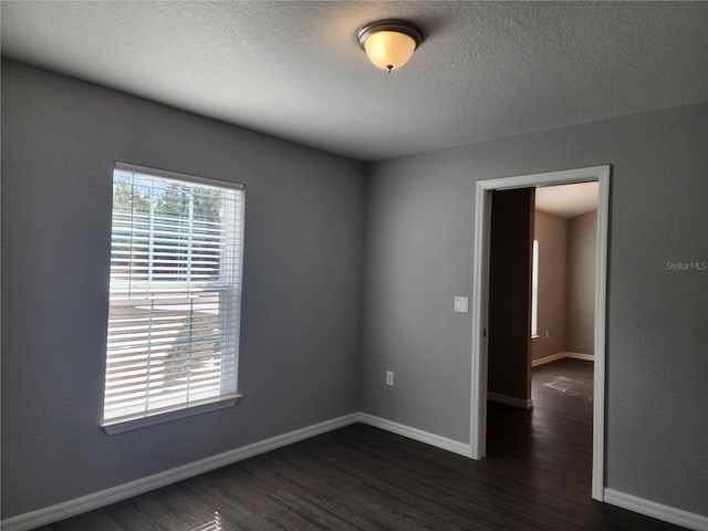 spare room with dark hardwood / wood-style floors and a textured ceiling