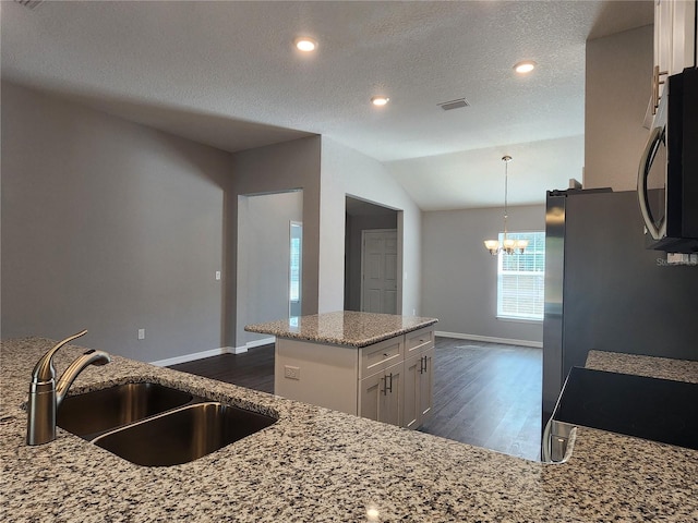 kitchen with sink, appliances with stainless steel finishes, a kitchen island, light stone countertops, and white cabinets