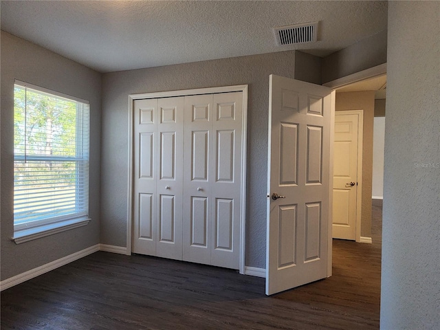 unfurnished bedroom featuring dark hardwood / wood-style flooring, a closet, and a textured ceiling