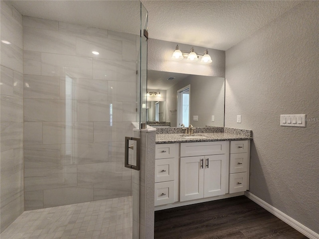 bathroom featuring wood-type flooring, vanity, a textured ceiling, and walk in shower