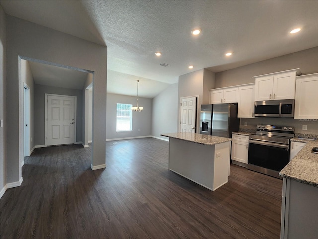 kitchen with a kitchen island, white cabinetry, appliances with stainless steel finishes, and light stone counters