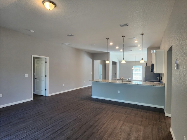 kitchen with white cabinetry, light stone counters, decorative light fixtures, a textured ceiling, and dark hardwood / wood-style floors