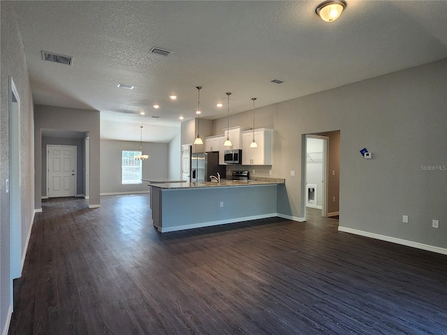 kitchen featuring dark wood-type flooring, kitchen peninsula, pendant lighting, stainless steel appliances, and white cabinets