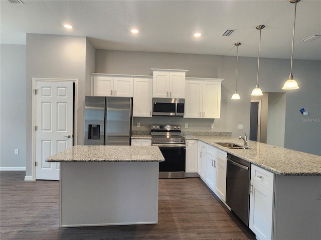 kitchen with pendant lighting, appliances with stainless steel finishes, light stone counters, white cabinets, and kitchen peninsula