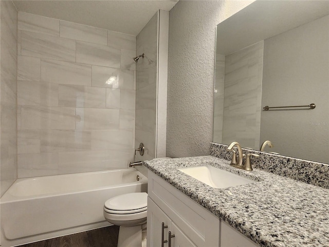 full bathroom featuring vanity, hardwood / wood-style floors, tiled shower / bath combo, and toilet