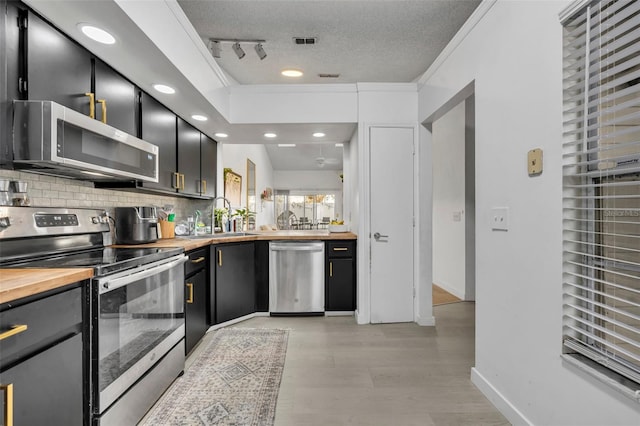 kitchen featuring appliances with stainless steel finishes, wood counters, sink, ornamental molding, and a textured ceiling