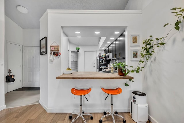 bar with stainless steel appliances, butcher block countertops, and light hardwood / wood-style flooring