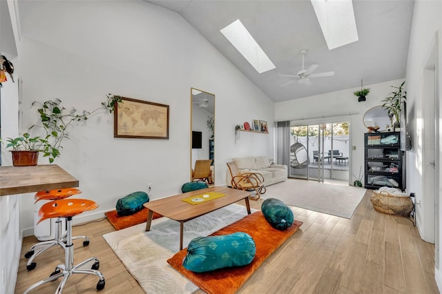 interior space featuring light hardwood / wood-style flooring, a skylight, high vaulted ceiling, and ceiling fan