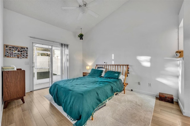 bedroom featuring lofted ceiling, light hardwood / wood-style flooring, ceiling fan, access to exterior, and a textured ceiling