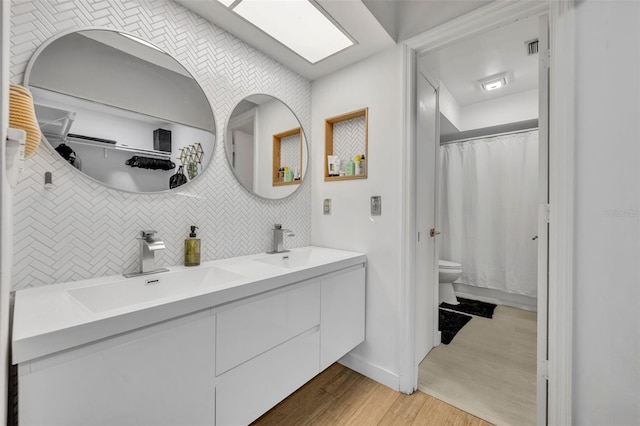 bathroom with vanity, hardwood / wood-style flooring, a skylight, and toilet