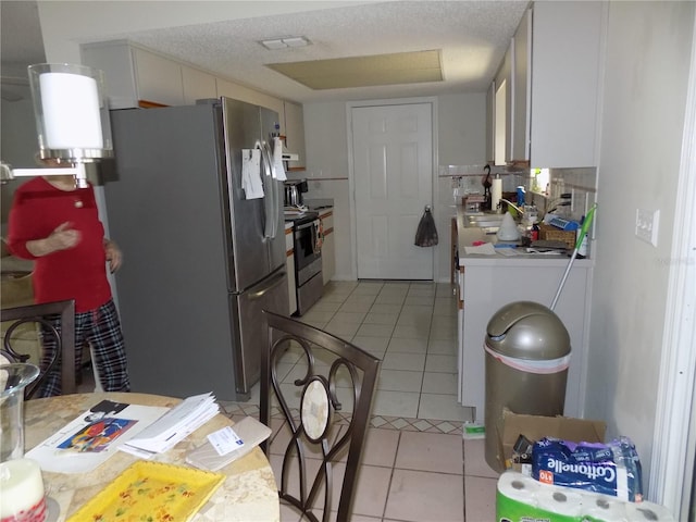 kitchen with white cabinetry, stainless steel appliances, light tile patterned flooring, and sink