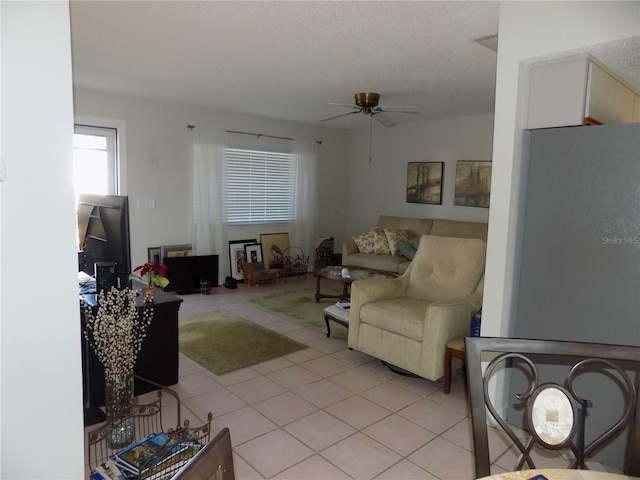 living room with light tile patterned flooring, ceiling fan, and a textured ceiling