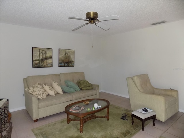 living room with ceiling fan, light tile patterned floors, and a textured ceiling