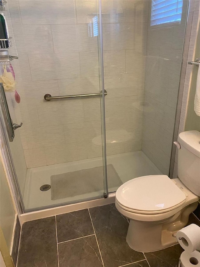 bathroom with toilet and a shower with door