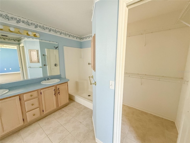 bathroom featuring double vanity, a stall shower, a sink, and tile patterned floors