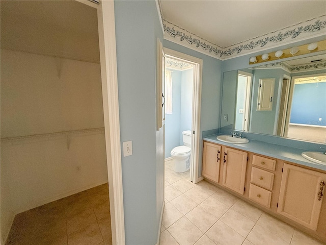 bathroom featuring tile patterned flooring, a sink, toilet, and double vanity