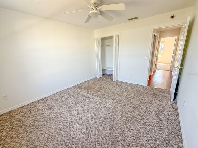 unfurnished bedroom featuring baseboards, visible vents, ceiling fan, carpet floors, and a closet