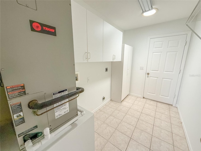 clothes washing area with cabinet space, heating unit, hookup for a washing machine, hookup for an electric dryer, and light tile patterned flooring