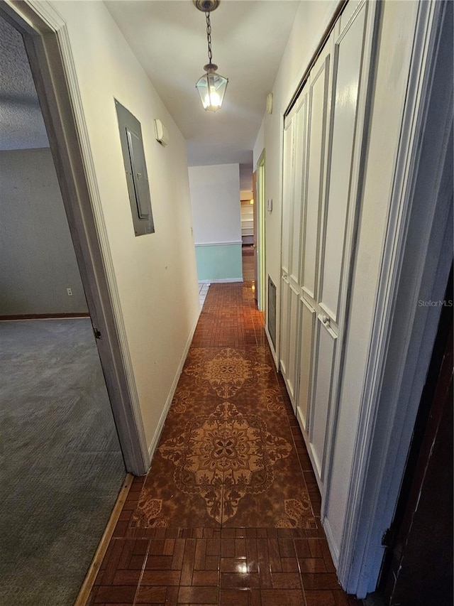 hallway featuring electric panel and dark carpet