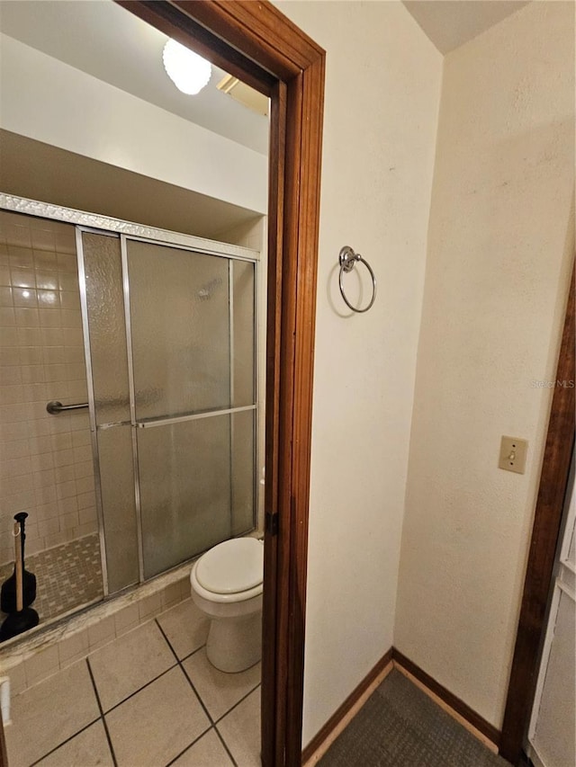 bathroom featuring walk in shower, tile patterned floors, and toilet