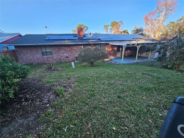 rear view of house with a yard, a patio area, and solar panels