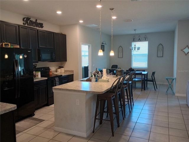 kitchen featuring light tile patterned flooring, sink, a breakfast bar area, black appliances, and a center island with sink