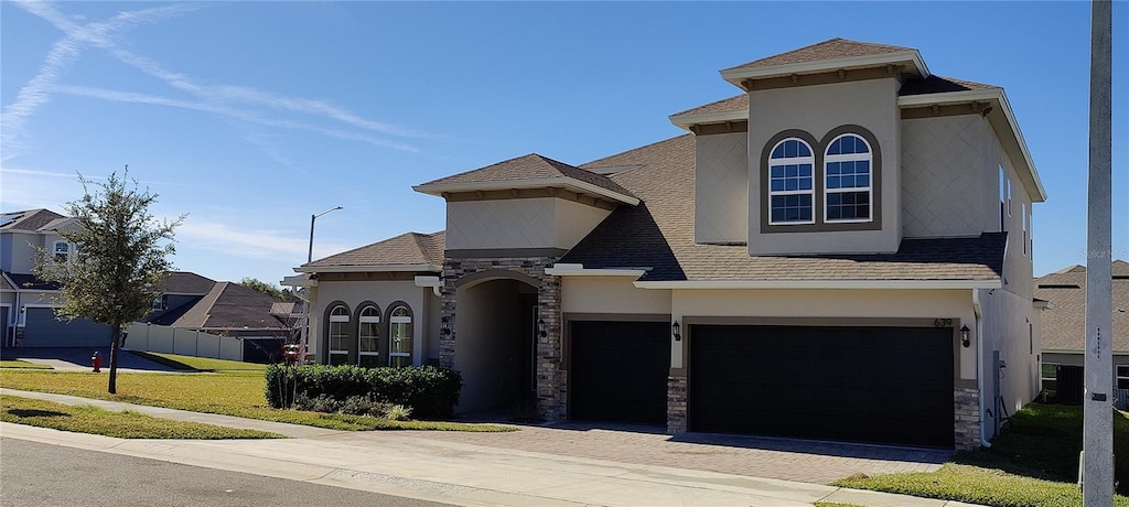 mediterranean / spanish home featuring a garage and a front lawn