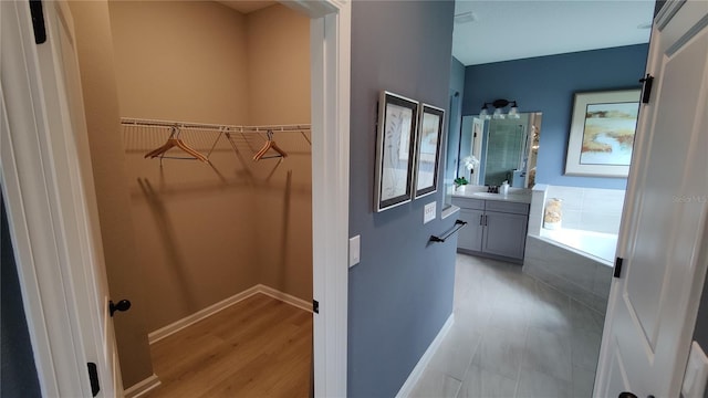 bathroom featuring vanity, hardwood / wood-style floors, and tiled tub