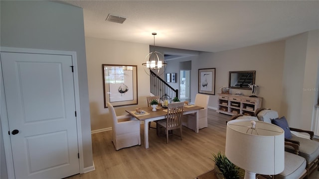 dining room with light hardwood / wood-style flooring and a chandelier