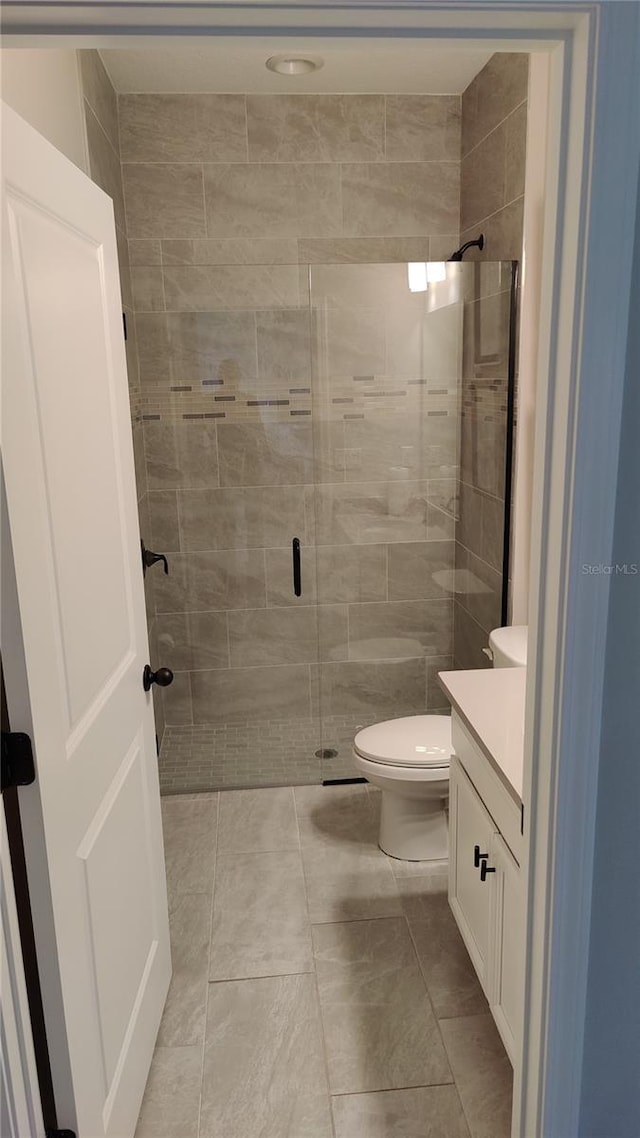 bathroom with walk in shower, vanity, toilet, and tile patterned flooring